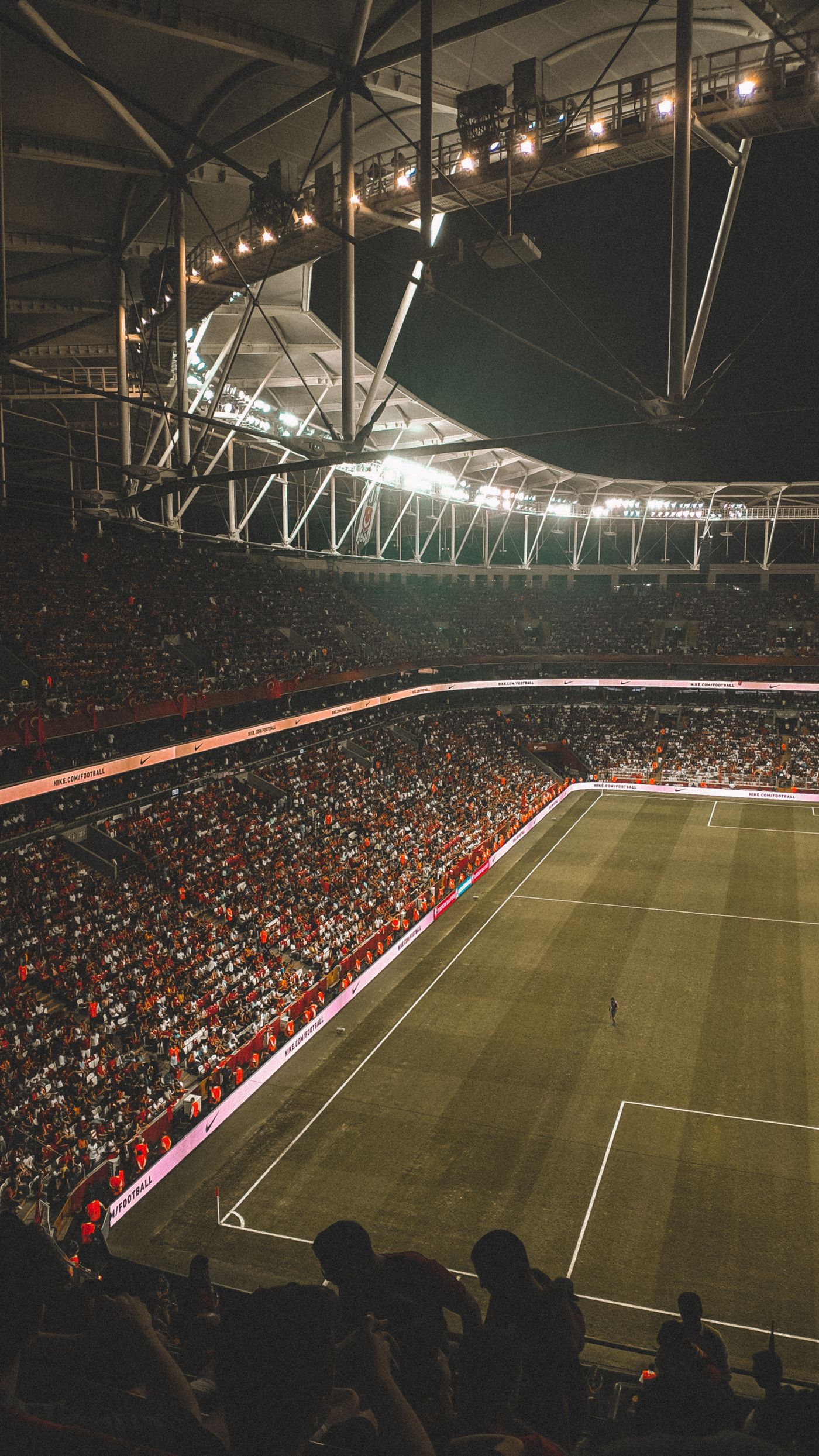 Football fans watching an evening match in a floodlit stadium